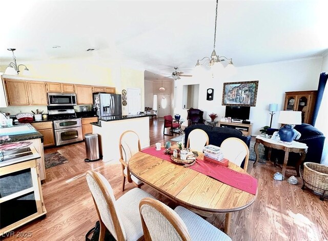 dining room featuring lofted ceiling, light hardwood / wood-style floors, ceiling fan with notable chandelier, and sink