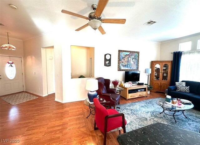 living room featuring ceiling fan, wood-type flooring, crown molding, and a textured ceiling