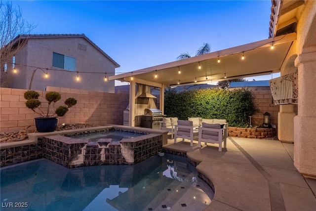 pool at dusk with an in ground hot tub, an outdoor kitchen, grilling area, an outdoor fireplace, and a patio area