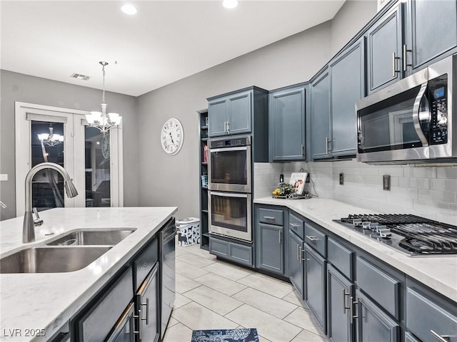 kitchen featuring stainless steel appliances, pendant lighting, sink, an inviting chandelier, and tasteful backsplash