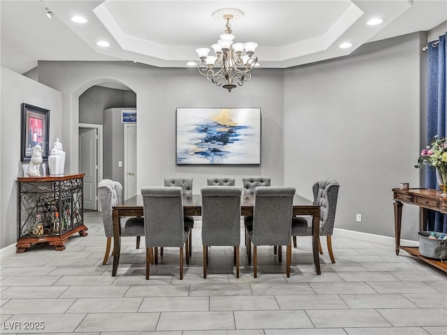 dining area with a notable chandelier and a raised ceiling