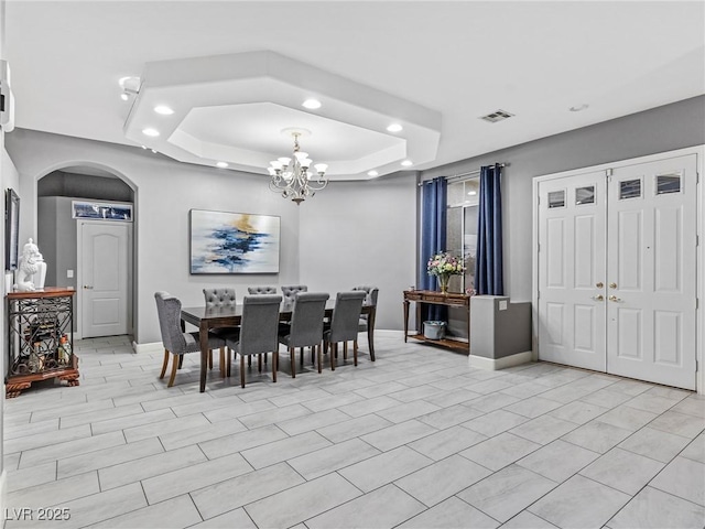 dining area featuring a raised ceiling and an inviting chandelier