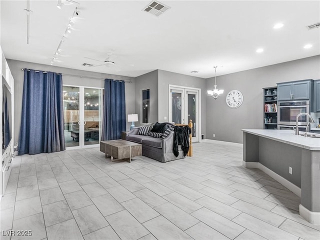 living room featuring ceiling fan with notable chandelier, rail lighting, and french doors