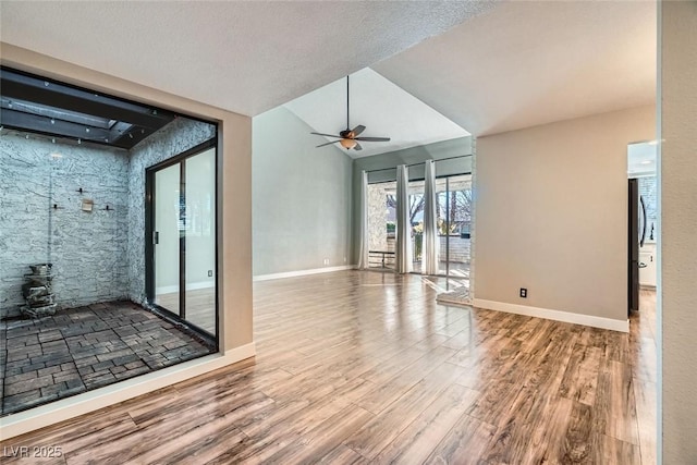 empty room with ceiling fan, lofted ceiling, a textured ceiling, and wood-type flooring