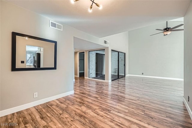 empty room with ceiling fan with notable chandelier and hardwood / wood-style floors