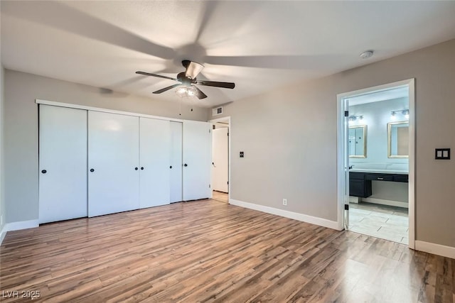 unfurnished bedroom featuring ensuite bath, a closet, ceiling fan, and light hardwood / wood-style flooring