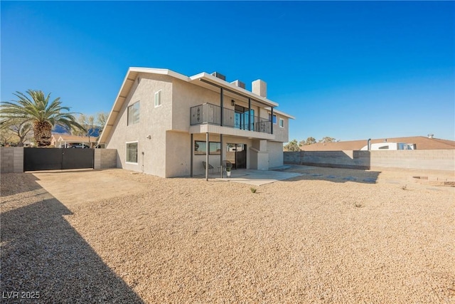 rear view of property featuring a balcony and a patio