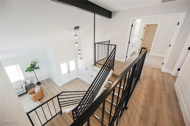 staircase with french doors, lofted ceiling with beams, and hardwood / wood-style floors