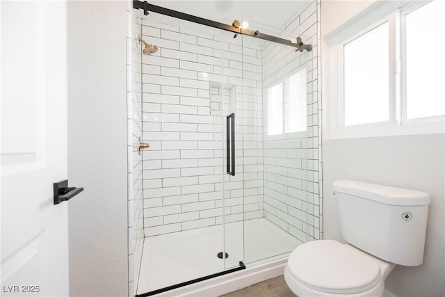 bathroom featuring toilet and a shower with shower door