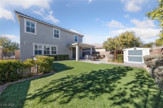 rear view of property featuring a lawn, a storage unit, and a patio area