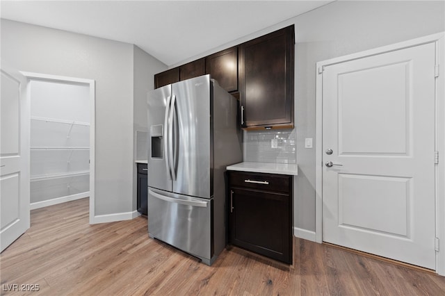 kitchen featuring stainless steel fridge with ice dispenser, light hardwood / wood-style flooring, dark brown cabinets, and decorative backsplash