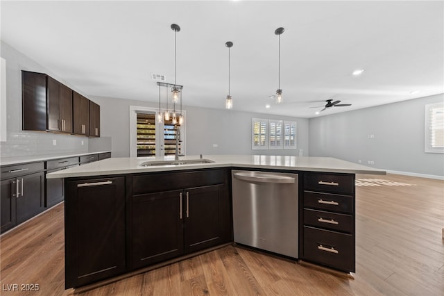 kitchen with stainless steel dishwasher, decorative light fixtures, a center island with sink, ceiling fan, and dark brown cabinetry