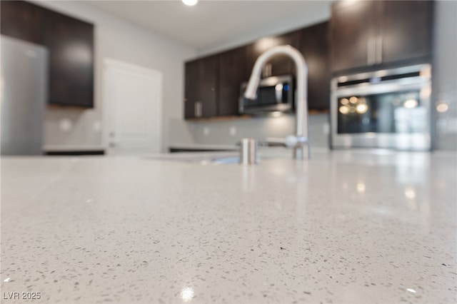 interior details with light stone countertops and dark brown cabinets