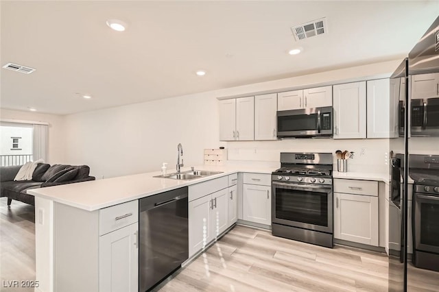 kitchen featuring sink, stainless steel appliances, light hardwood / wood-style flooring, and kitchen peninsula