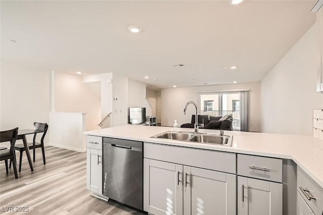 kitchen with stainless steel dishwasher, sink, and light hardwood / wood-style floors