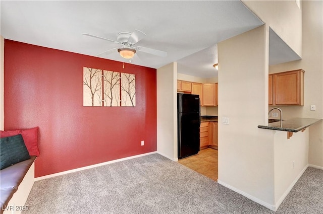 kitchen featuring sink, black refrigerator, light carpet, ceiling fan, and light brown cabinetry