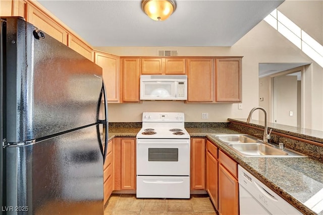 kitchen featuring white appliances, dark stone countertops, light tile patterned floors, and sink