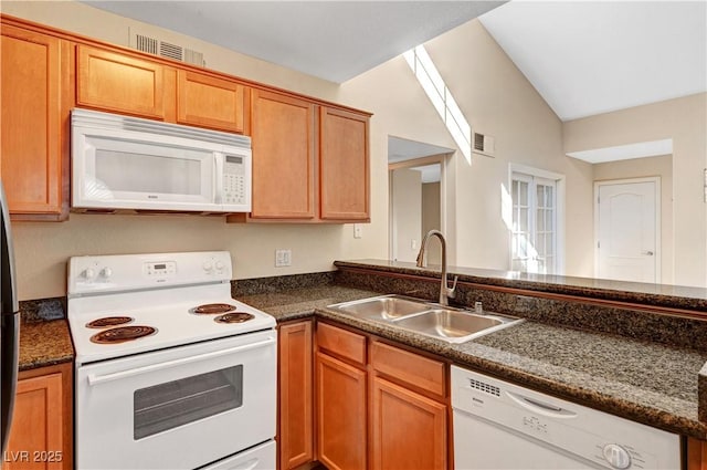 kitchen with sink, white appliances, lofted ceiling, and dark stone counters