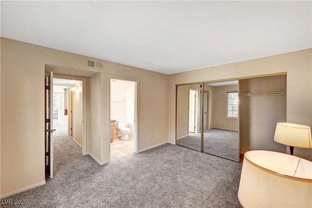 unfurnished bedroom featuring ensuite bathroom, a closet, and light carpet