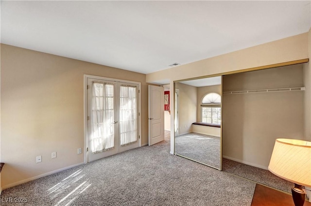 unfurnished bedroom with french doors, a closet, and carpet