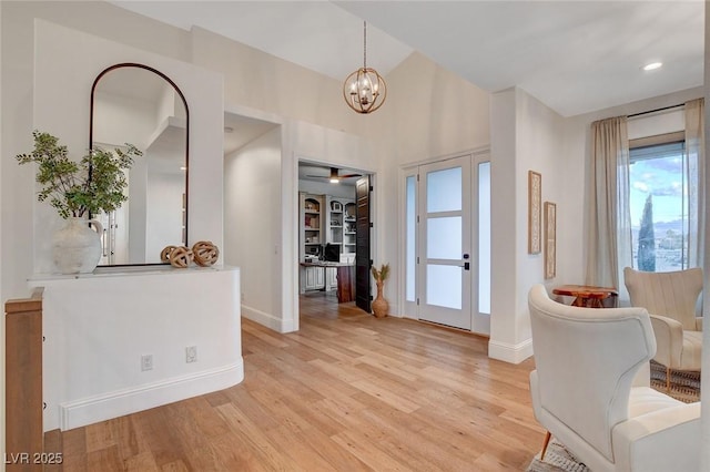 entryway with lofted ceiling, an inviting chandelier, and light hardwood / wood-style floors