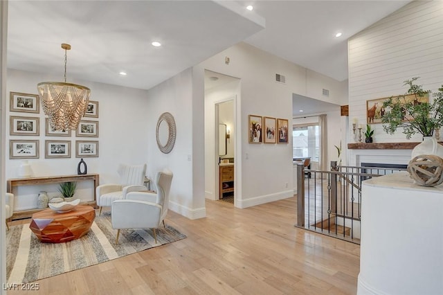 living area with light hardwood / wood-style flooring, an inviting chandelier, and vaulted ceiling