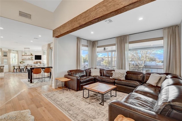 living room featuring beam ceiling and light hardwood / wood-style floors