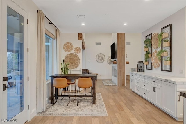 bar featuring white cabinets and light hardwood / wood-style flooring