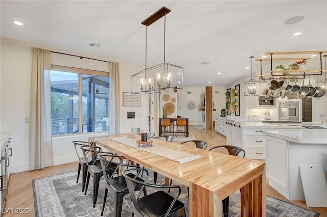 dining area with light hardwood / wood-style floors, sink, and a chandelier