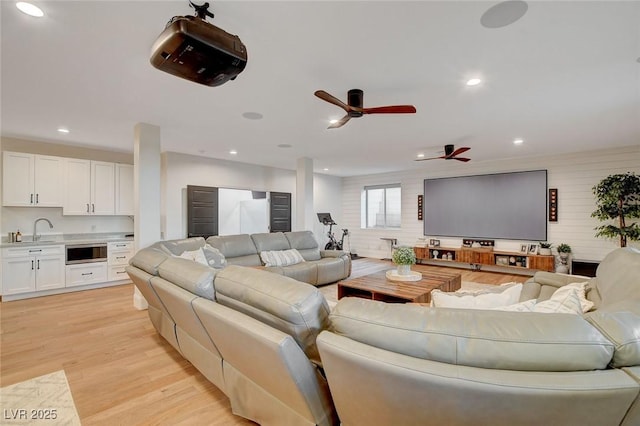 living room with sink, ceiling fan, and light hardwood / wood-style floors