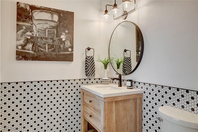 bathroom featuring tile walls, vanity, and toilet