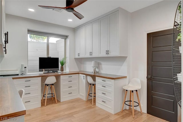 office area featuring light wood-type flooring, ceiling fan, and built in desk