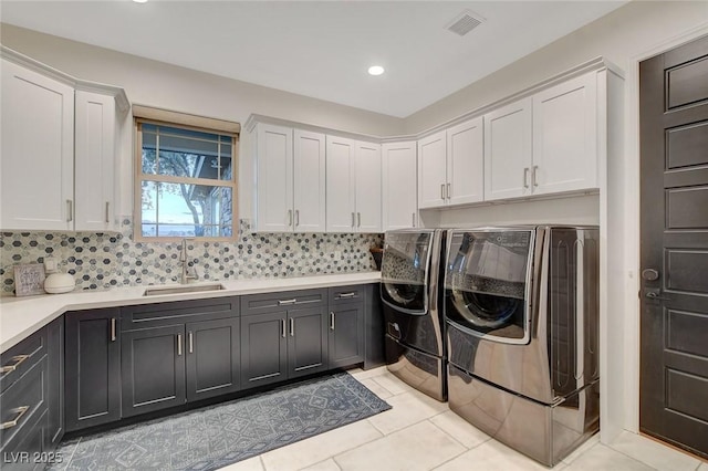 laundry room with sink, washer and dryer, light tile patterned floors, and cabinets