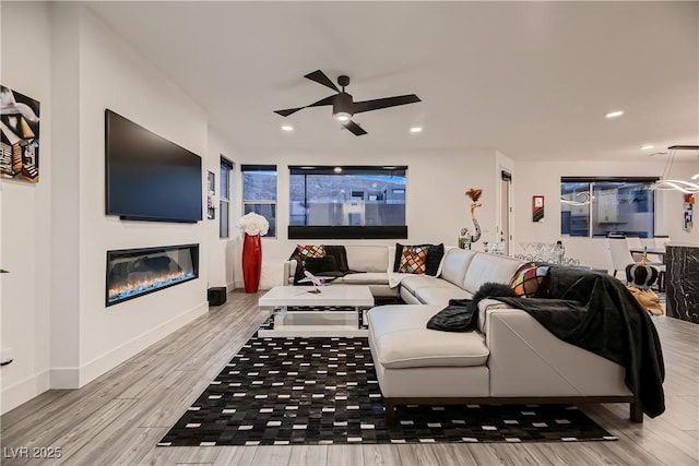 6289 Redstone Hills Dr, Las Vegas, NV 89148 - living room featuring a ceiling fan, wood finished floors, a glass covered fireplace, recessed lighting, and baseboards