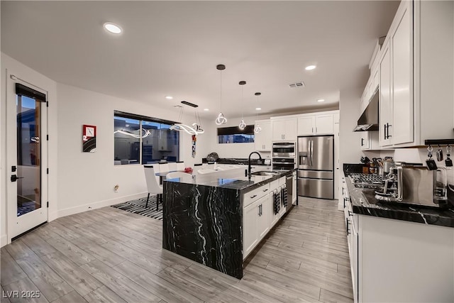 6289 Redstone Hills Dr, Las Vegas, NV 89148 - kitchen with stainless steel refrigerator with ice dispenser, a sink, under cabinet range hood, light wood-style flooring, and a center island with sink