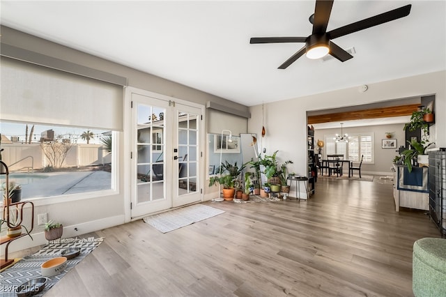 interior space with wood-type flooring, ceiling fan with notable chandelier, and french doors