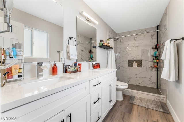 bathroom with hardwood / wood-style floors, tiled shower, vanity, and toilet