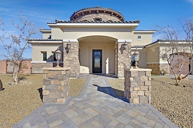 property entrance with stucco siding, stone siding, and a tiled roof