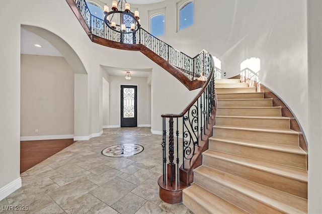 foyer entrance with french doors, a towering ceiling, and a chandelier