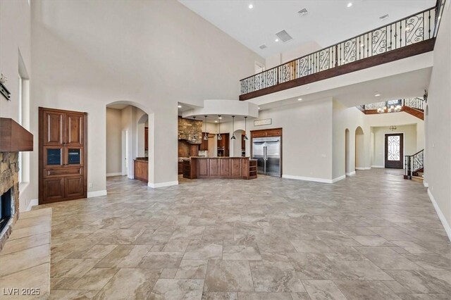 unfurnished living room featuring a towering ceiling and a fireplace