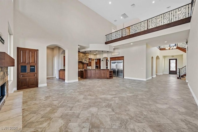 unfurnished living room with visible vents, baseboards, a fireplace, arched walkways, and stairs