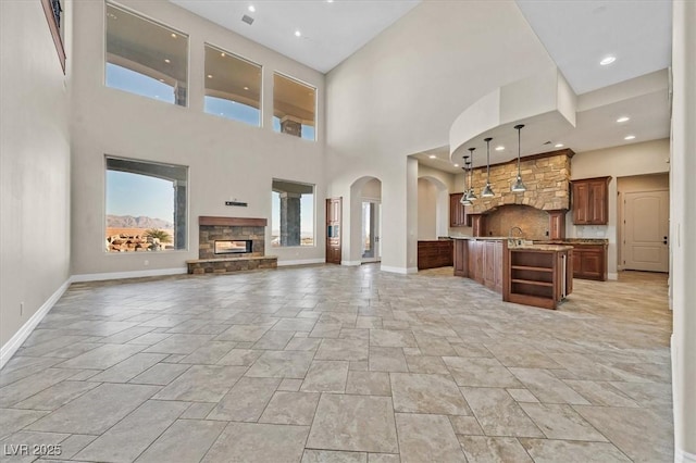 unfurnished living room with a high ceiling, a healthy amount of sunlight, and a stone fireplace