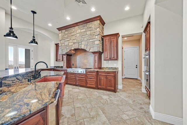 kitchen featuring sink, french doors, dark stone countertops, pendant lighting, and appliances with stainless steel finishes