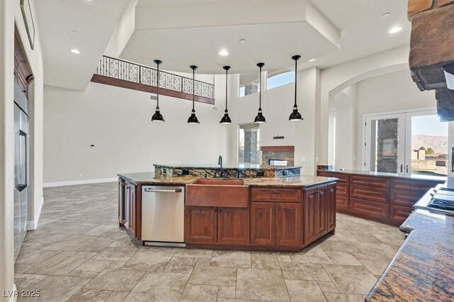 kitchen featuring stainless steel dishwasher, decorative light fixtures, a towering ceiling, a kitchen island, and sink