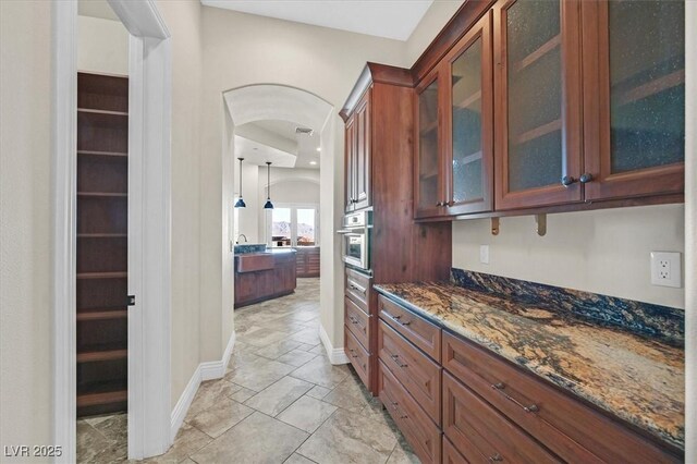 kitchen with oven, hanging light fixtures, and dark stone counters