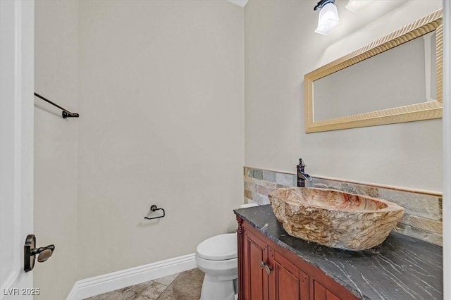 bathroom with toilet, vanity, and baseboards