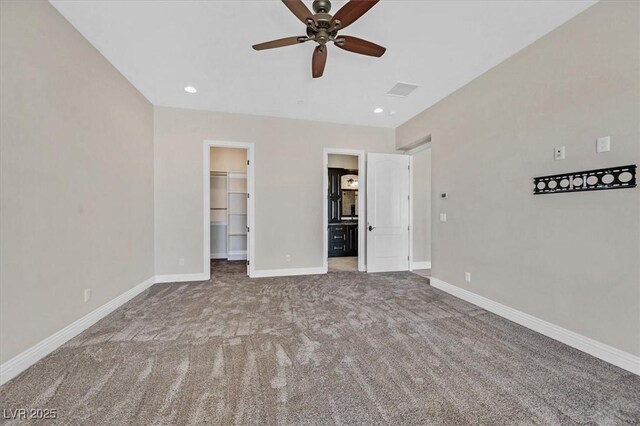 unfurnished bedroom with carpet flooring, ceiling fan, a spacious closet, and a closet