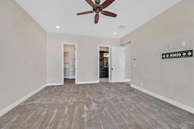 unfurnished bedroom with recessed lighting, a walk in closet, baseboards, and carpet floors