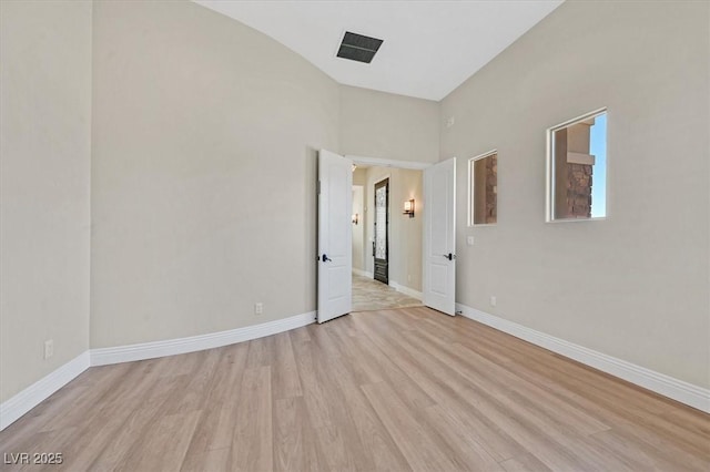 empty room with light wood-type flooring, baseboards, and visible vents