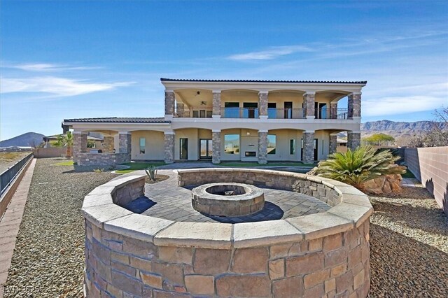 view of front of property with a balcony, an outdoor fire pit, and a mountain view